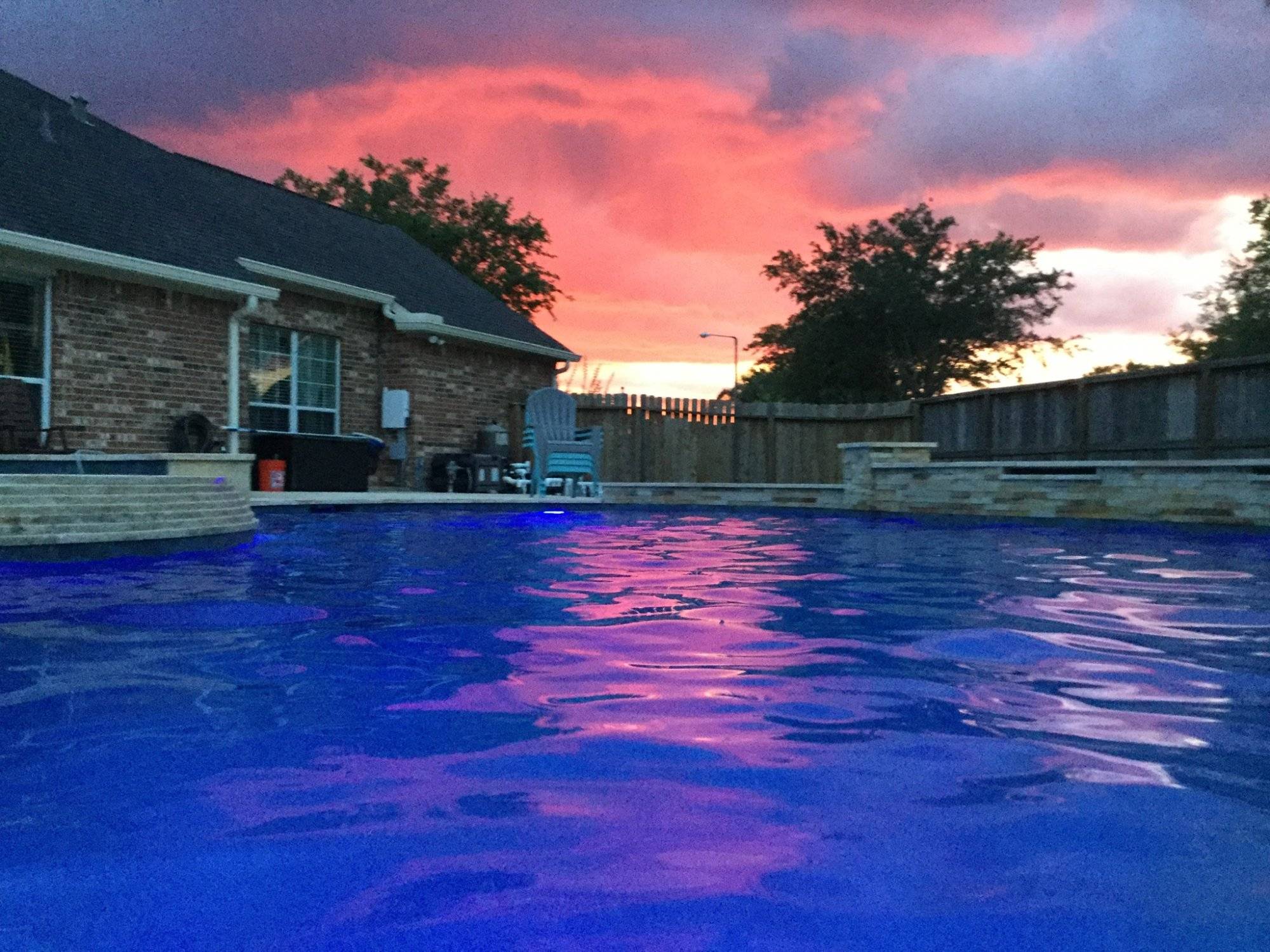 A red sunset over a clear blue swimming pool